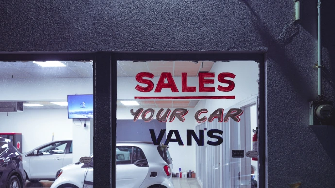 a car dealership with a sales sign in the window